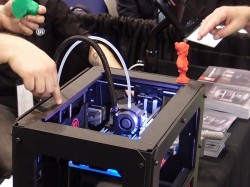 Pohled do útrob designově vyladěného MakerBot Replicatoru 2. To modré světlo nemá žádný praktický význam, prostě je “cool”. Barva se dá změnit výměnou osvětlovacích diod. Foto: Jan Homola